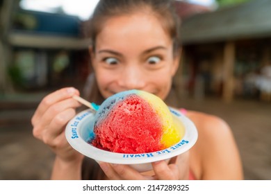 Hawaiian shave ice happy woman tourist making funny face hungry eating sweet frozen snow cone local dessert food of Hawaii