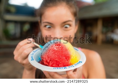 Hawaiian shave ice happy woman tourist making funny face hungry eating sweet frozen snow cone local dessert food of Hawaii