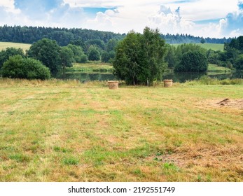 Hay Bales On Mowed Meadow Near River After Summer Rain