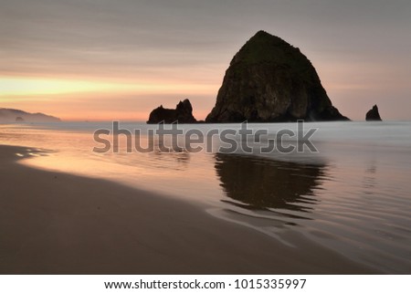 Haystack Rock Beach Sunrise. Sunrise at Haystack Rock in Cannon Beach, Oregon as the surf washes up onto the beach. United States.


