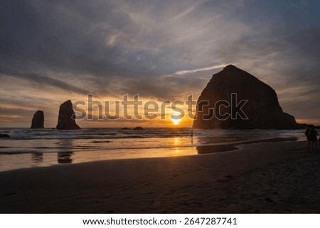 Haystack Rock at Cannon Beach during an Autum sunset. Sun silhouettes the rock with dramtic colors.