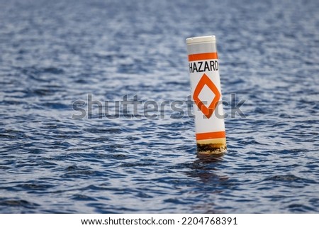 Hazard safety buoy alerting boaters to navigation danger. Nautical warning caution float.