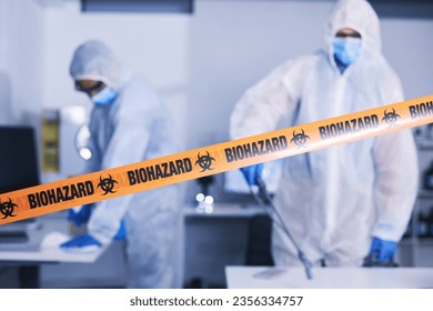 Hazard, tape and people in danger working with toxic, biology or team disinfect dangerous bacteria or health emergency. Biohazard, protection and medical staff in hazmat suit cleaning for bio safety