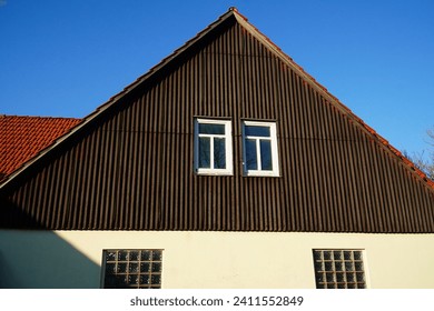 Hazardous asbestos on an old house gable. Old building material for wall cladding. This material is banned because of the cancer risk posed by the microfibers. Village of Juehnde, Germany.