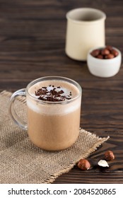 Hazelnut moсacсino coffee in a glass mug on a wooden table.