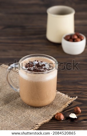 Hazelnut moсacсino coffee in a glass mug on a wooden table.