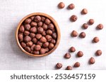 Hazelnut kernels, also known as cobnuts and filberts, in a wooden bowl on linen. Whole, dried and shelled nuts, fruits of the hazel tree Corylus avellana. Ready to eat as snack ,and to use for baking.