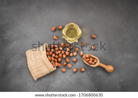Hazelnuts, filbert in burlap sack and hazelnut oil in glass of bottle on rustic backdrop. heap or stack of hazelnuts. Hazelnut background, healty food