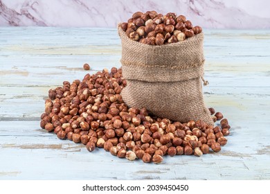 Hazelnuts In Linen Sack Bag, Hazelnut Farm In The Background, Inner Hazelnuts Spilled On The Table