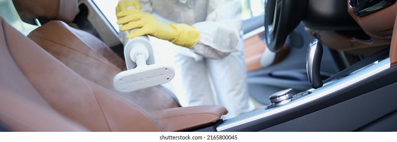 Hazmat Worker Cleansing Car Interior With Spray Disinfectant And Steam Heat