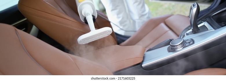 Hazmat Worker Cleansing Car Interior With Spray Disinfectant And Steam Heat