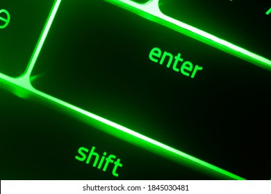 Hazy green illuminated keyboard enter and shift key closeup