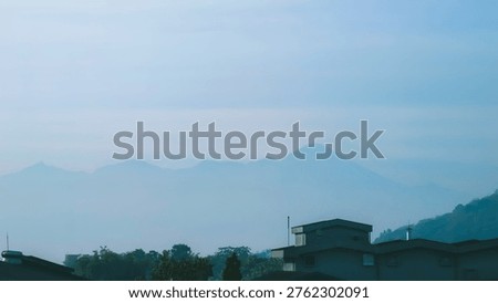 hazy mountain range behind rooftops and trees