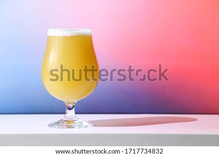 A hazy New England India pale ale beer in a tulip shaped glass against a soft background.