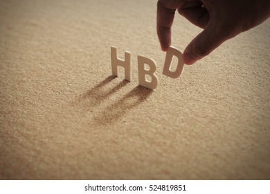 HBD word on compressed board with human's finger at D letter