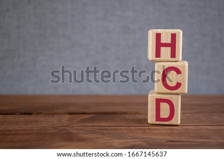 HCD (Human Capital Development) acronym on wooden cubes on dark wooden backround. Business concept.