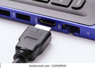 HDMI cable near the HDMI port of the modern blue laptop on a white background - Shutterstock ID 1139189033
