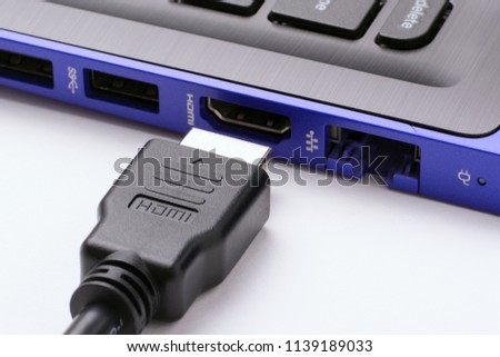 HDMI cable near the HDMI port of the modern blue laptop on a white background