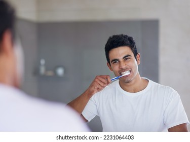 He brushes twice daily for optimal oral health. Shot of a young man brushing his teeth at home.