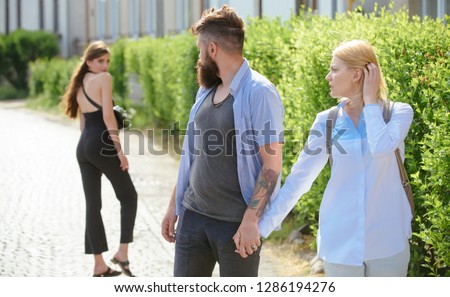 He is a cheater. Man cheating his wife or girlfriend. Love triangle and threesome. Bearded man looking at other girl. Hipster choosing between two women. Betrayal and infidelity. Unfaithful love.