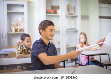 He Is Happy For The Good Grade. Teens In Class. The Teacher Gives Them Control Tasks.