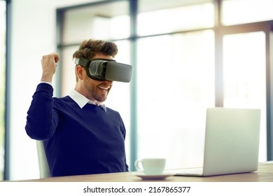 He Just Scored Another Win. Shot Of A Businessman Wearing A VR Headset And Doing A Fist Pump While Working In An Office.