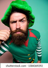 He Loves His Beard. Irish Pub Party. St Patricks Day. Serious Bearded Hipster In Green Hat. Christmas Elf. Brutal Man Touch His Beard. Ireland Beer Tradition. Winter Carnival. Barber Hair Care.