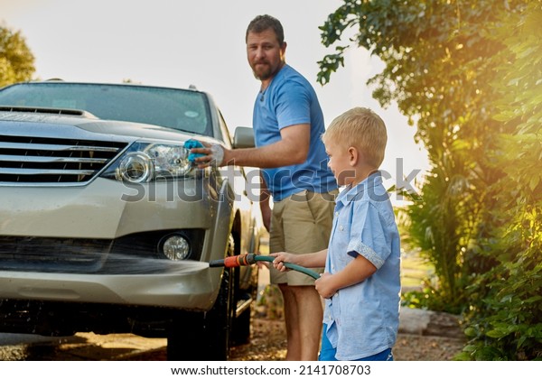 He may be young but hes\
still very helpful. Cropped shot of a father and son washing a car\
together.