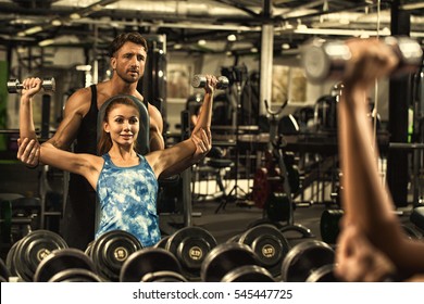 He Motivates Her. Handsome Mature Male Fitness Instructor Guiding His Female Client Beautiful Woman Exercising With Dumbbells At The Gym Fitness Personal Training Motivation Concept Copyspace