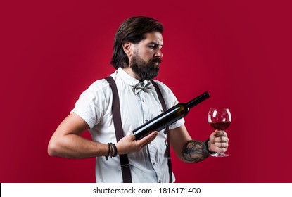 He Offers The Best. Elegant Male Barman. Handsome Hipster Drinking Wine Glass. Sommelier Tasting Alcohol. Bearded Man In Suspenders Drink Red Wine. Brutal Guy Bartender In Bow Tie.