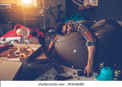 He is out. Young handsome man passed out on bean bag with joystick in his hand in messy room after party - Shutterstock ID 393546085