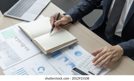 Head Of Accounting Is Recording The Company's Financial Growth Statistics Using Graphs As A Reference For Reviewing And Analyzing The Results, Taking Notes And Analyzing Data Graphs In Office.