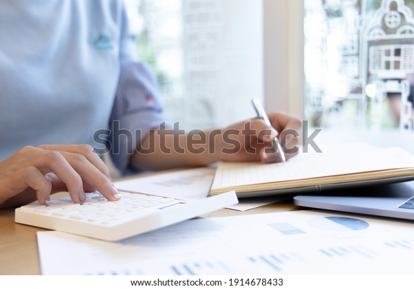 Head of accounting is recording the company\'s\
financial growth statistics using graphs as a reference for\
reviewing and analyzing the results, Taking notes and analyzing\
data graphs in office.