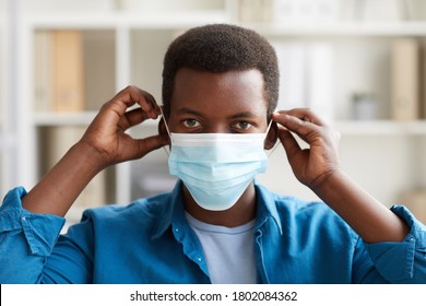 Head Ad Shoulders Portrait Of Young African-American Man Putting On Face Mask While Working In Post Pandemic Office