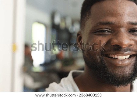 Head of appy african american man with beard standing and smiling in sunny house. Lifestyle,relaxation,free time and domestic life, unaltered.