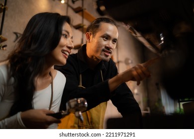 The Head Barista Is Training A Female Employee In Front Of A Coffee Machine.