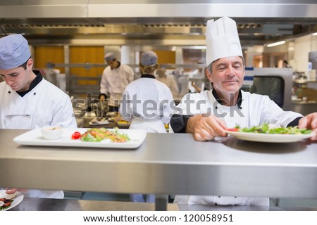 Head chef checking salad in the kitchen before service