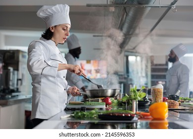 Head chef cooking gourmet dish for dinner service in restaurant professional kitchen. Food industry worker stirring in pan delicious food while preparing ingredients for meal recipe. - Powered by Shutterstock