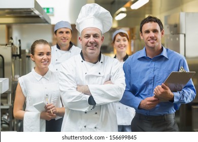 Head chef posing with the team behind him in a profesionnal kitchen