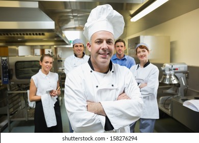 Head chef posing with team behind him in a professional kitchen
