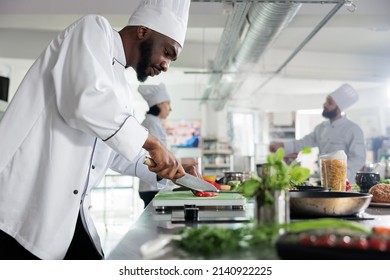 Head chef in restaurant professional kitchen preparing delicious meal. Food industry worker cutting fresh and organic vegetables while cooking gourmet dish for dinner service - Powered by Shutterstock