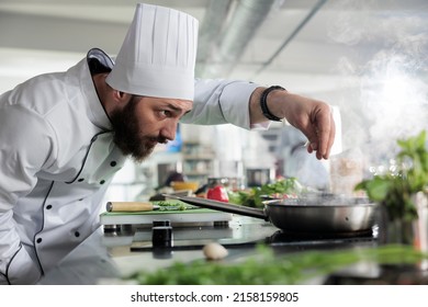 Head Chef Seasoning Gourmet Dish In Pan While Cooking Fine Dining Food Served At Dinner Service In Restaurant. Food Industry Worker Preparing Ingredients For Evening Meal In Professional Kitchen.