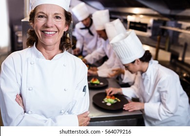 Head chef smiling in busy kitchen with team working behind him