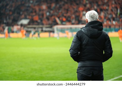 Head coach's back and soccer match at the stadium in the background. - Powered by Shutterstock