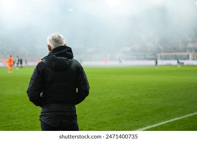 Head coach's back and soccer match at the stadium in the background. - Powered by Shutterstock