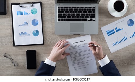 Head of department reading business contract attentively, top view of workplace - Shutterstock ID 1086803117