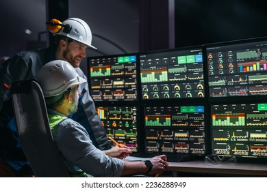 Head engineer and factory operator following product process on factory uses SCADA system and industry 4.0. Two operators controll assembly line using screens with human-machine interface