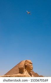 The Head Of The Great Sphynx Of Giza With A Passanger Plane Flying Over It.