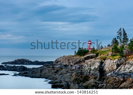 The Head Harbour Lightstation shines brightly on a gloomy morning at low tide. Also known as the East Quoddy Head. Campobello Island, New Brunswick, Canada.