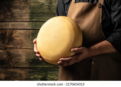 A head of hard cheese in man's cheesemaker hands. delicious dairy products. cheese maasdam with big holes. - Shutterstock ID 2170654313